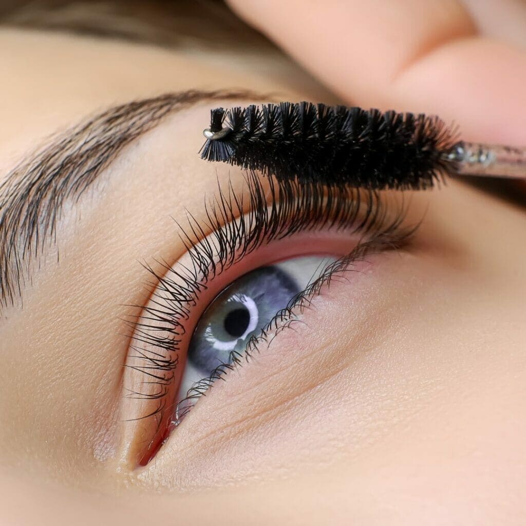 Female client receiving lash service at Fabulously Beautiful in Sutton Valence. We offer brow wax, tint & pmu services, lash lifts and lash tints. Image depicts a lash wand being used to brush through client's lashes.